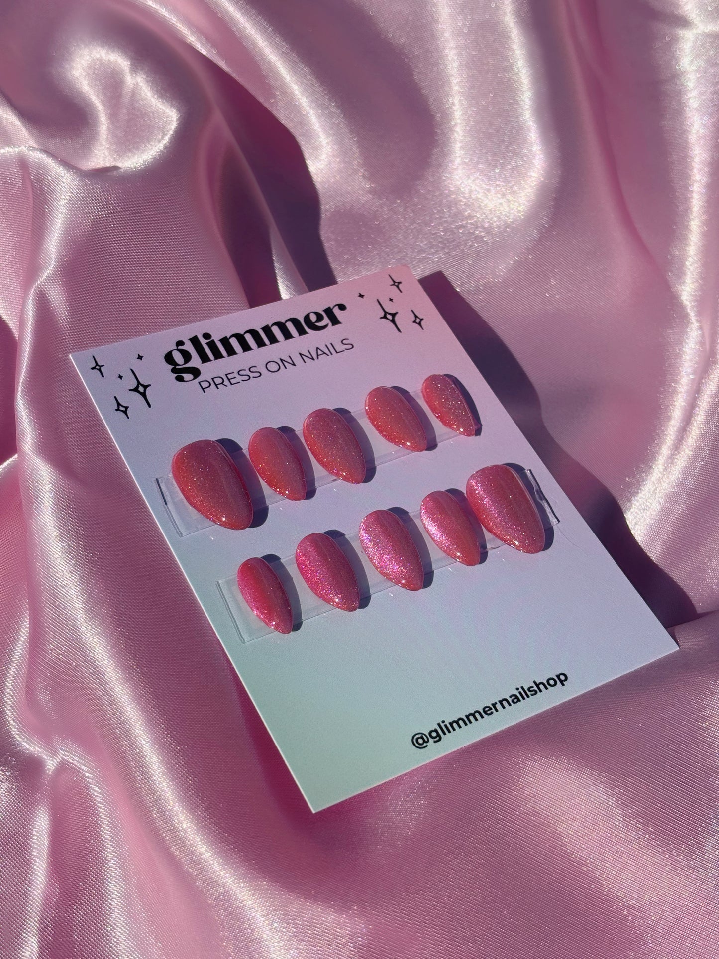 Card with press-on nails displayed on a pink satin background