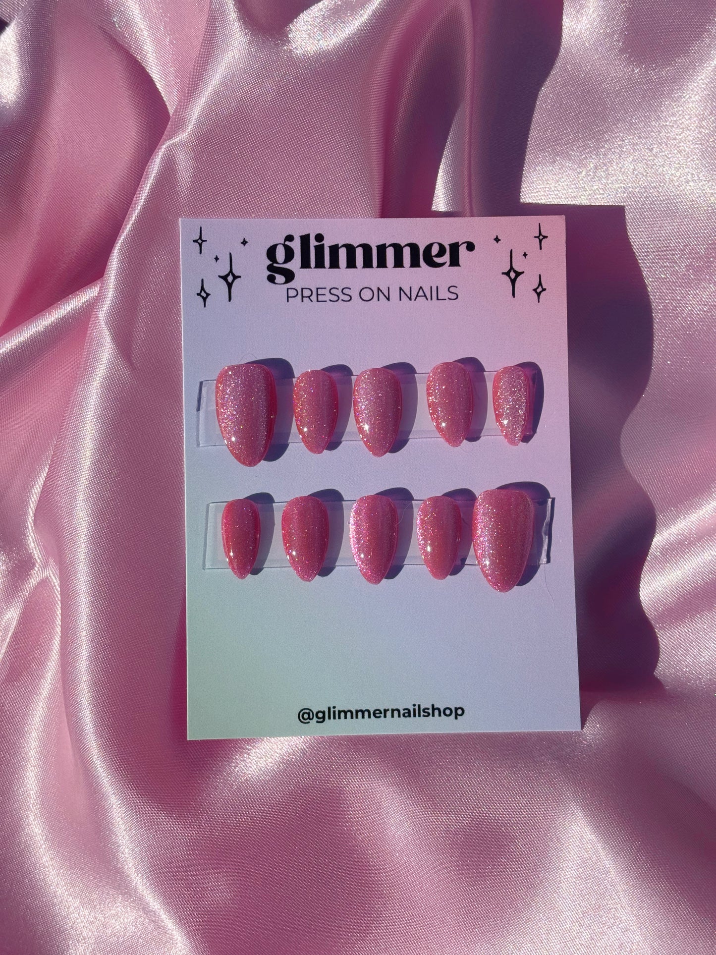 Glimmer press on nails packaging on a pink satin background
