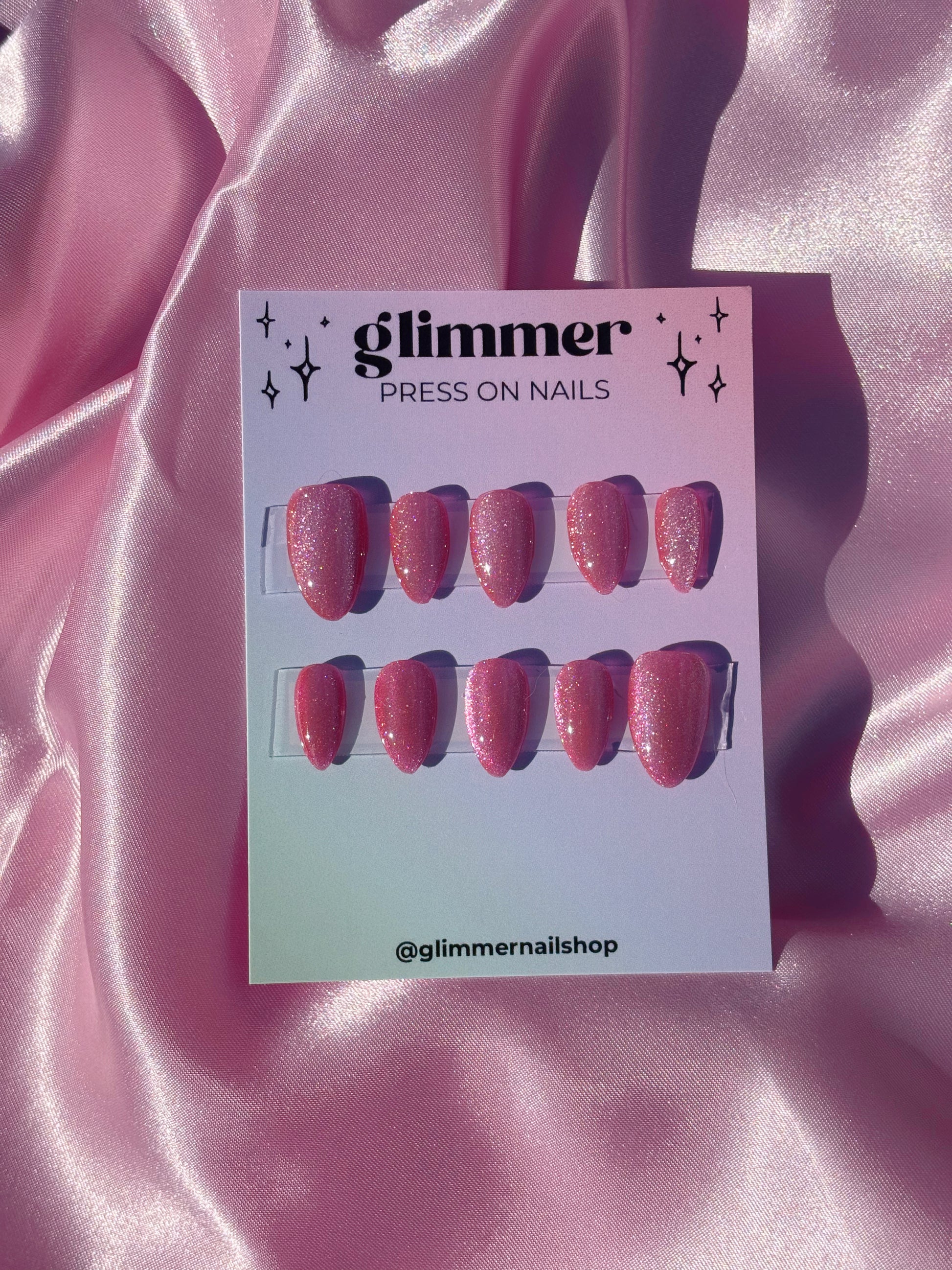 Glimmer press on nails packaging on a pink satin background